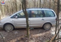 zdjęcie przedstawia samochód zaparkowany  w lesie i przykryty gałęźmi