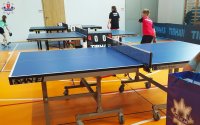 zdjęcie przedstawia stół do tenisa stołowego a przy nim grający chłopcy