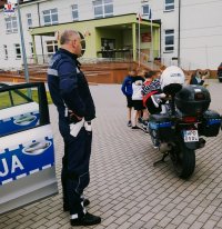 zdjęcie przedstawia policjanta z ruchu drogowego z dziećmi a przy nim motocykl
