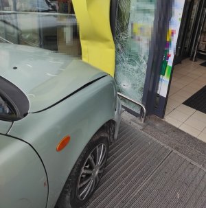 uszkodzone auto i drzwi sklepu